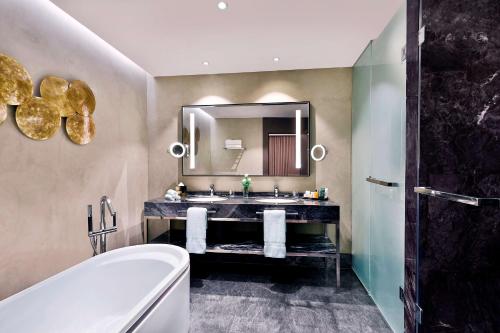 丹吉尔Hilton Tanger City Center的一间带水槽、浴缸和镜子的浴室