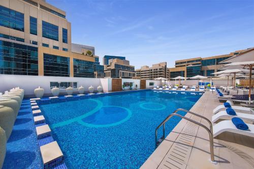 迪拜迪拜希尔顿逸林酒店 - 商务湾的大楼内带躺椅的大型游泳池