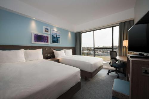 爱丁堡爱丁堡西区希尔顿汉普顿酒店的酒店客房设有两张床、一张桌子和一台电视。