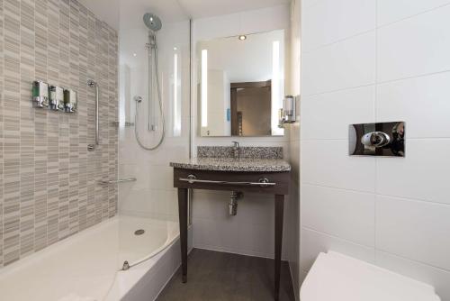 爱丁堡爱丁堡西区希尔顿汉普顿酒店的浴室配有盥洗盆和带镜子的淋浴