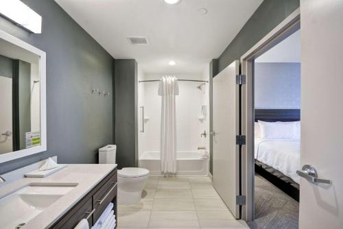 普莱诺Home2 Suites By Hilton Plano Richardson的浴室设有床、卫生间和水槽。