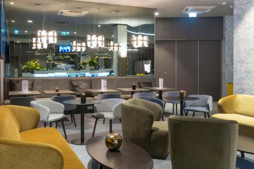 波兹南Hampton By Hilton Poznan Old Town的餐厅设有桌椅和吊灯。