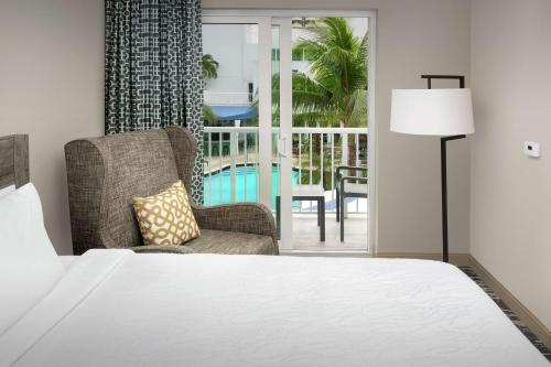 迈阿密厄尔巴诺迈阿密酒店的一间带一张床和一把椅子的卧室以及一个阳台