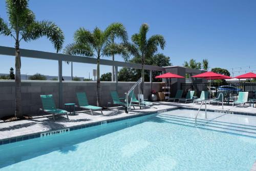 奥兰多Home2 Suites By Hilton Orlando Airport的一个带椅子和遮阳伞的游泳池