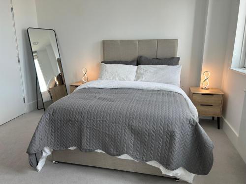 伦敦Luxurious two-bedroom flat with scenic views的一间卧室配有一张带灰色棉被和镜子的床