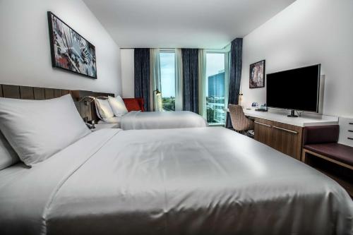 西棕榈滩Hilton Garden Inn West Palm Beach I95 Outlets的酒店客房设有一张大床和一台电视。