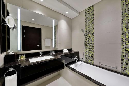 多哈Doubletree By Hilton Doha - Al Sadd的带浴缸、水槽和镜子的浴室