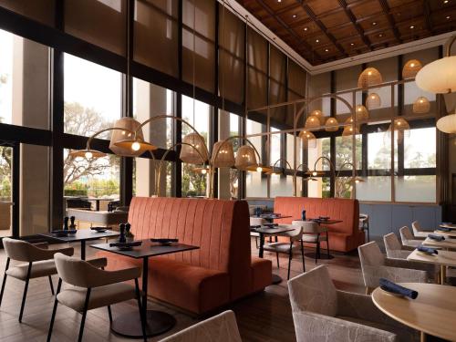 安纳海姆Hotel Fera Anaheim, a DoubleTree by Hilton Hotel的餐厅设有桌椅和大窗户。