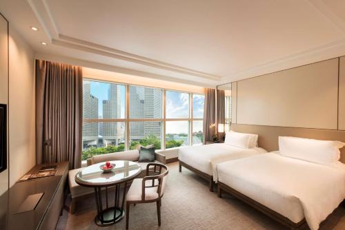 新加坡Conrad Centennial Singapore的酒店客房设有两张床和一张桌子。