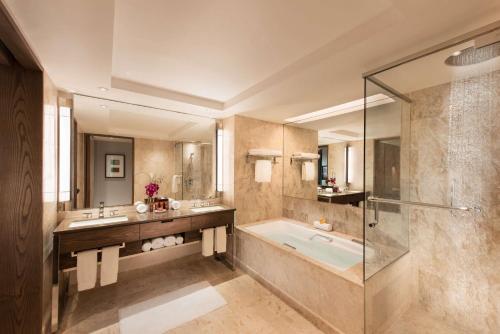 新加坡Conrad Centennial Singapore的带浴缸、两个盥洗盆和淋浴的浴室。
