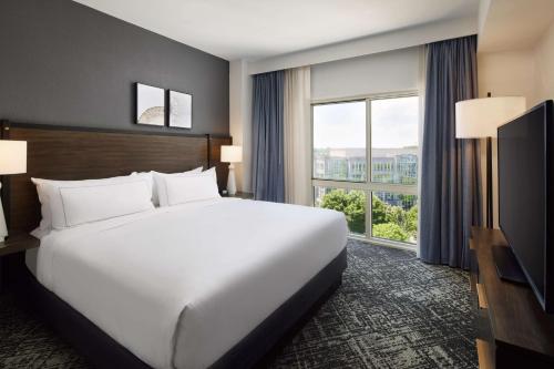 夏洛特Hilton Charlotte Airport Hotel的一张大白色床,位于酒店带大窗户的房间里