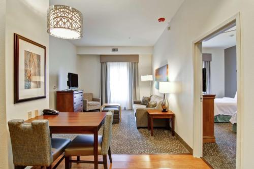 俄克拉何马城西俄克拉荷马城希尔顿惠庭套房酒店的一间带桌子的客厅和一间带床的房间