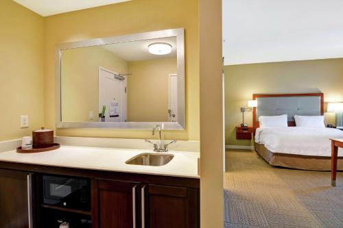 查尔斯顿Hampton Inn & Suites Charleston Airport的一间带水槽的浴室和一间带一张床的卧室