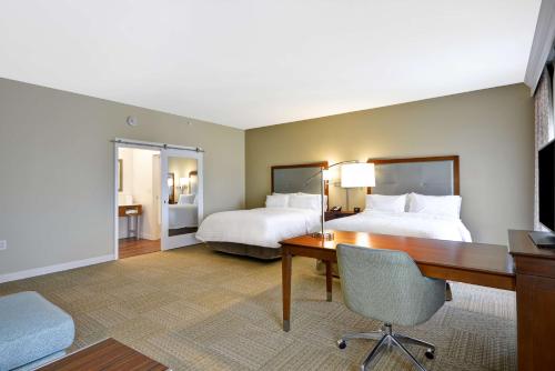 查尔斯顿Hampton Inn & Suites Charleston Airport的大型酒店客房设有两张床和一张书桌