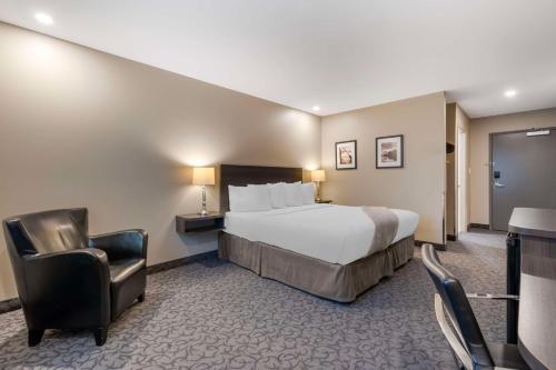 赫斯特Villa Inn & Suites - SureStay Collection by Best Western的配有一张床和一把椅子的酒店客房
