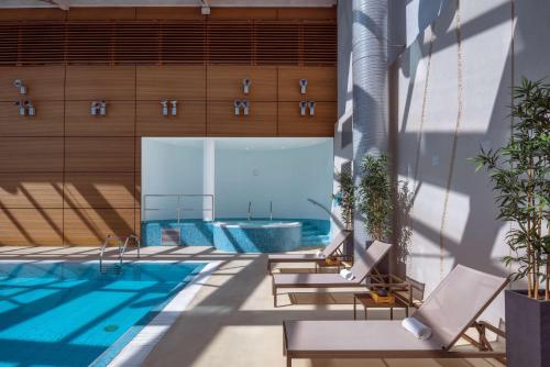 日内瓦Hilton Geneva Hotel and Conference Centre的享有带椅子的游泳池和游泳池的景色