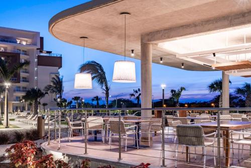 棕榈滩Embassy Suites By Hilton Aruba Resort的庭院内的餐厅,配有桌椅