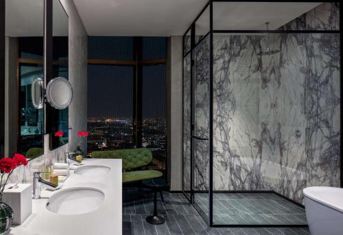 迪拜DoubleTree by Hilton Dubai M Square Hotel & Residences的一间带两个盥洗盆和淋浴的浴室