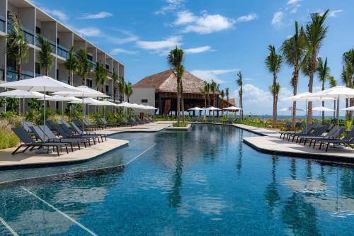 图卢姆Hilton Tulum Riviera Maya All-Inclusive Resort的度假酒店的游泳池配有椅子和遮阳伞