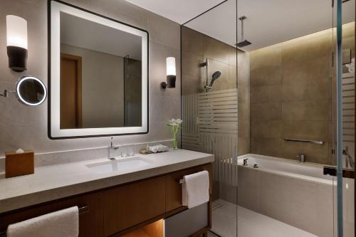 沙迦DoubleTree by Hilton Sharjah Waterfront Hotel And Residences的一间带水槽、浴缸和镜子的浴室