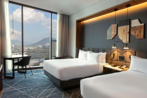 蒙特雷Hilton Monterrey的酒店客房配有两张床和一张书桌