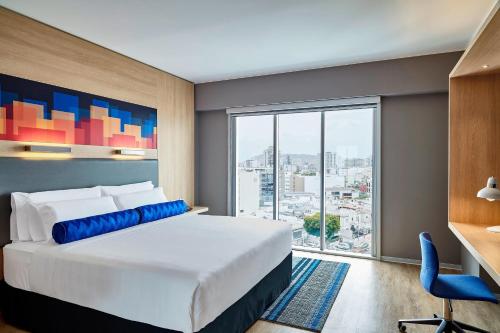 利马Aloft Lima Miraflores的一间卧室配有一张床、一张书桌和一个大窗户
