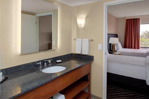 凤凰城Embassy Suites by Hilton Phoenix Scottsdale的一间带水槽和床的酒店浴室