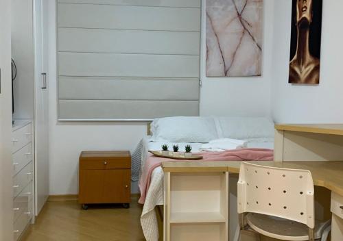 坎皮纳斯Studio completo com vaga entre o Centro e Cambuí的客房设有书桌和带桌子的床。