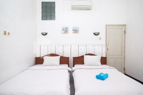 SentoolHotel Limaran 1 Syariah Malioboro Mitra RedDoorz的两张带白色床单和蓝色玩具的床