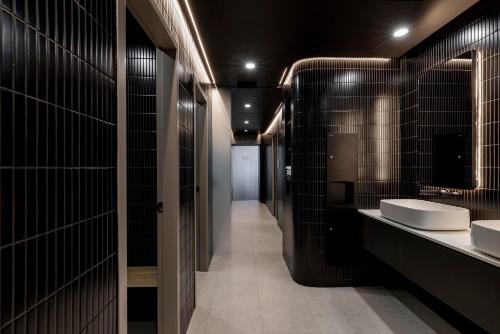 悉尼Citadines Walker North Sydney的浴室设有两个水槽和黑色瓷砖墙壁。