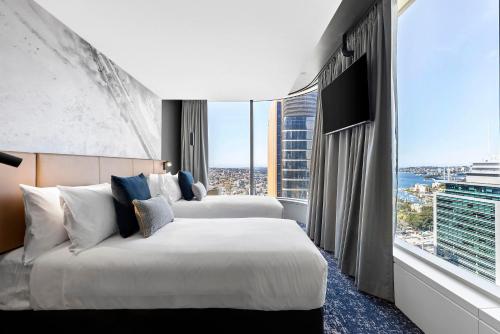 悉尼Citadines Walker North Sydney的酒店客房设有两张床和大窗户。