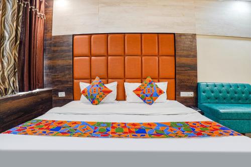 NaiāpuraFabHotel Brij Residency的一间卧室配有一张带橙色床头板的大床