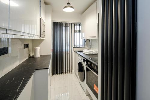 米查姆CommonSide Luxury的厨房配有白色橱柜、洗衣机和烘干机