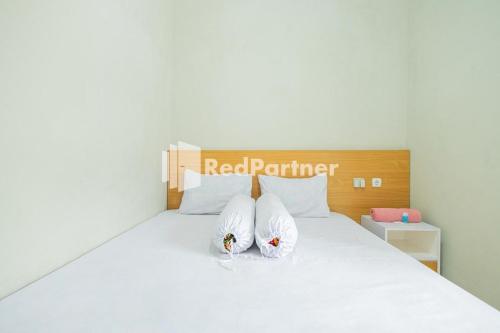 西冷Atiq Homestay Syariah Mitra RedDoorz的卧室配有白色的床和2个枕头