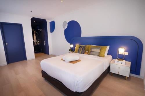 八打灵再也Ukiyo Hotel的一间卧室配有一张大床和蓝色床头板