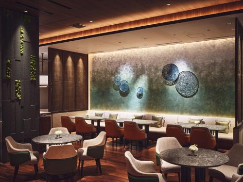 八幡平市ANA InterContinental Appi Kogen Resort, an IHG Hotel的餐厅设有桌椅,墙上挂有绘画作品
