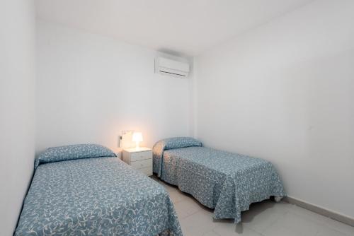 马拉加Casa Mar de frente的白色客房的两张床,配有蓝色棉被