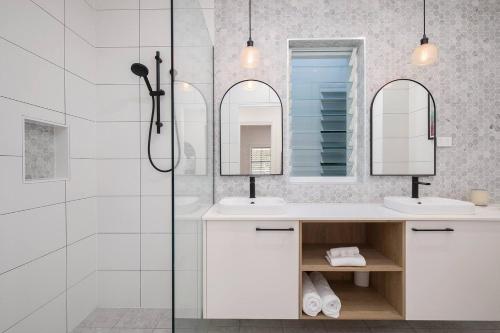 纽卡斯尔Poolside Glamour - A Stylish Newcastle Hideaway的一间带两个盥洗盆和淋浴的浴室
