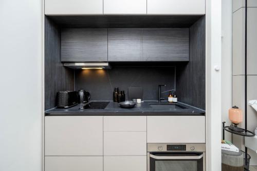 哈罗Spacious Studio Apartments at Dandi on The Hill的厨房配有黑白橱柜和炉灶。