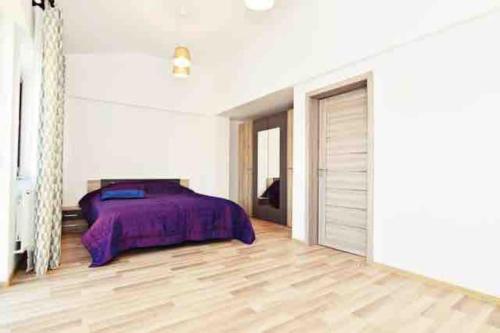 雅西Casa Albert 2的一间卧室配有一张紫色的床,铺有木地板
