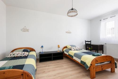 GuipavasMaison neuve au centre-ville proche de l'aéroport的卧室设有两张床,拥有白色的墙壁和木地板