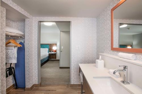 干岭德赖里奇希尔顿恒庭酒店的一间带水槽和镜子的浴室以及一间卧室