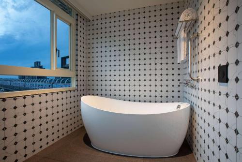 林口区新北林口爵怡温德姆酒店-MRT(A9)机场捷运A9林口站的带窗户的浴室内的白色浴缸
