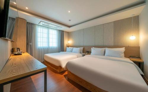 釜山Adena Hotel的酒店客房设有两张床和窗户。