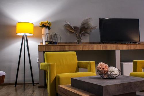 大特尔诺沃R34 Boutique Guest House的客厅配有黄色椅子、桌子和电视