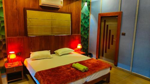 KottakkalDAYA AYURVILLAGE的一间卧室配有一张带两盏灯的床和一台电视