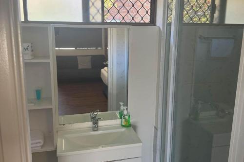 雷德克利夫KippaRing Village Motel (Near Redcliffe)的浴室配有盥洗盆和带镜子的淋浴