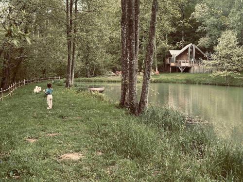 Les Croix CheminsCasa Slow avec sa piscine chauffée au bord du lac的站在湖边草地上的男孩