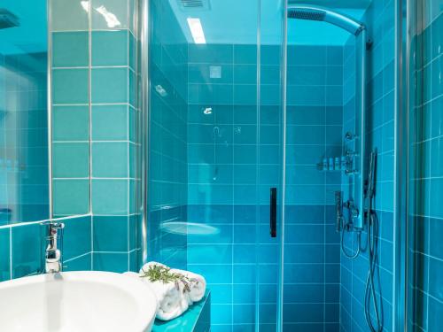 巴特斯欧天堂设计公寓式酒店的蓝色瓷砖浴室设有水槽和淋浴