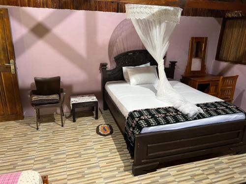 内布拉拉Lualemba Bungalows的一间卧室配有一张床和一把椅子